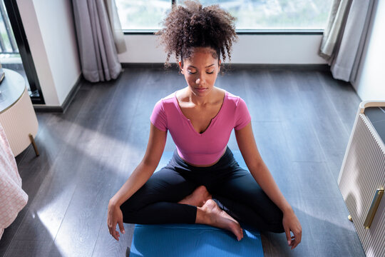 Woman practicing mindfulness meditation on a blue yoga mat