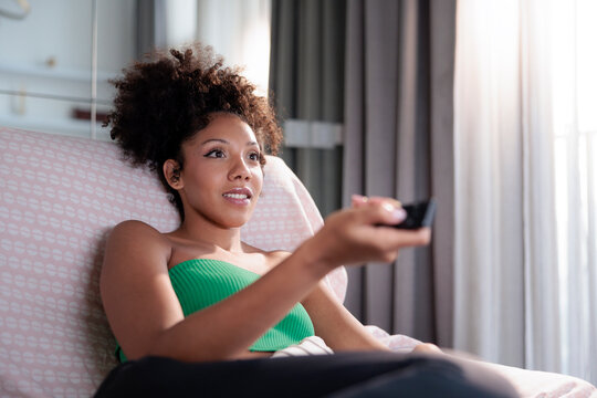 Young woman using a remote control to watch television