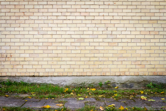 Yellow brick wall background with green grass. Architectural detail.
