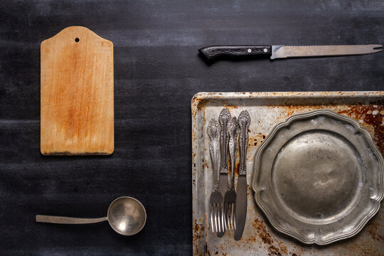 Old various kitchen utensils on black chalkboard background. Food themed flat lay.