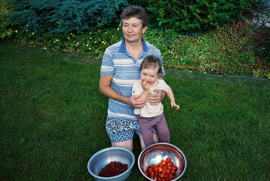 Grandmother with granddaughter and two bowls of fresh berries
