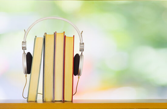 audiobooks concept with  stack of books and headphones blurry bokeh balls and soft colored background
