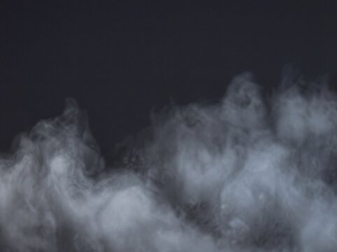 Gray smoke plumes rise against a dark blurred background