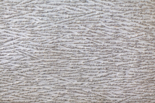 Silver Wavy Raised Texture on White Surface. Close view of a white surface with raised silver wavy lines forming an irregular textured pattern.