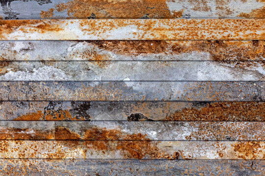 Weathered Rusted Metal Panels with Industrial Patina. Close view of weathered metal strips with gray surfaces, orange rust, corrosion, and mottled industrial.