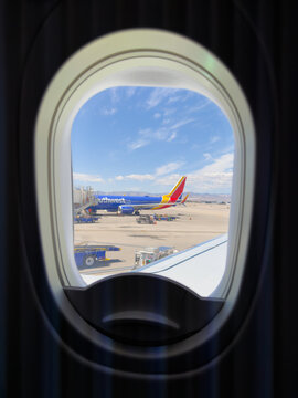 LAS VEGAS, NV, APR 28, 2026: View through an airplane window showing a parked Southwest Airlines jet, jet bridge, and ground equipment on the tarmac
