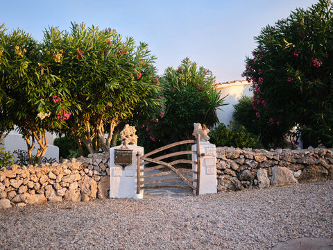 Rustic wooden gate in stone wall with oleander shrubs