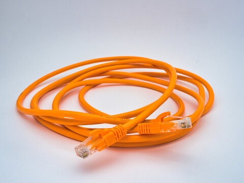 Orange Ethernet Cable Connector Close-up - A detailed close-up shot of an orange Ethernet cable with an RJ45 connector, highlighting network connectivity and technology on a white bac
