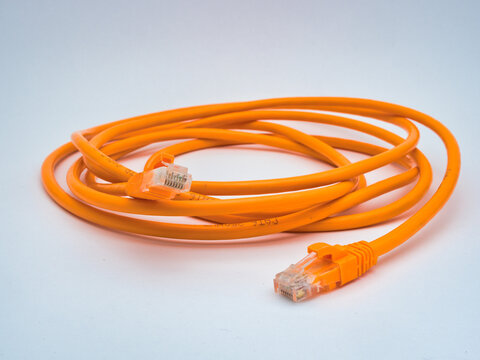 Orange Ethernet Cable Coiled on White - A bright orange Cat6 Ethernet patch cable is neatly coiled on a clean white background, showcasing its RJ45 connectors.