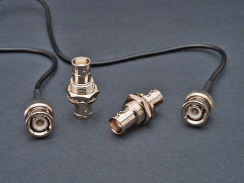 BNC Connectors and Coaxial Cable - Close-up studio shot of BNC connectors and coaxial cable on a dark grey background, essential components for video and data transmission.