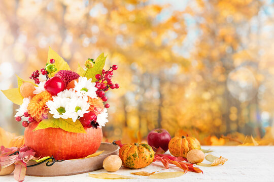 Autumn bouquet in a pumpkin vase on a wooden table for Thanksgiving