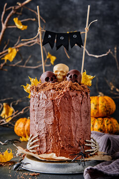 Halloween chocolate cake with skulls, skeleton hands and pumpkins at night