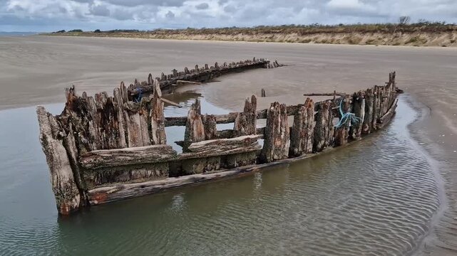 Wooden skeleton of an ancient shipwreck exposed at low tide on Cefn Sidan Beach in Pembrey Country Park, Carmarthenshire, South Wales, UK, maritime wreck stock video footage clip