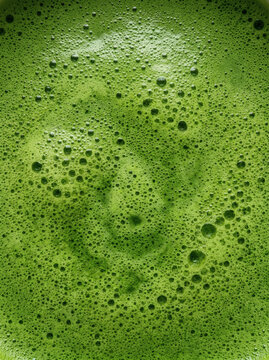 Vibrant green frothy liquid texture abstract background close up