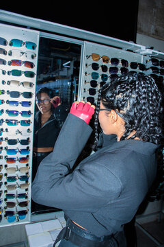 Woman Looking in Mirror While Trying on Sunglasses in a Store downtown