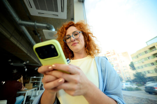 Young woman holds a mobile phone inside the university building