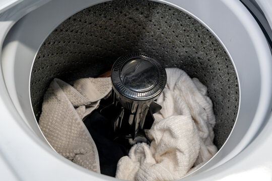 Open top-loading washing machine drum filled with dirty clothes, symbolizing laundry day, household chores, cleaning and everyday domestic life
