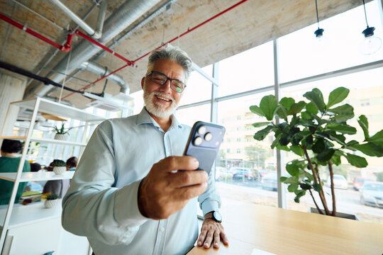 Older Man Checks His Phone Inside a Bright Indoor Space