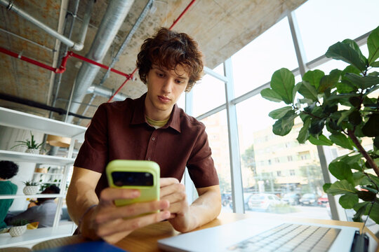 Young Man Using Smartphone in a Modern Workspace