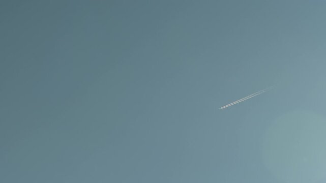 Passenger airplane flying high in sky leaving vapor trail