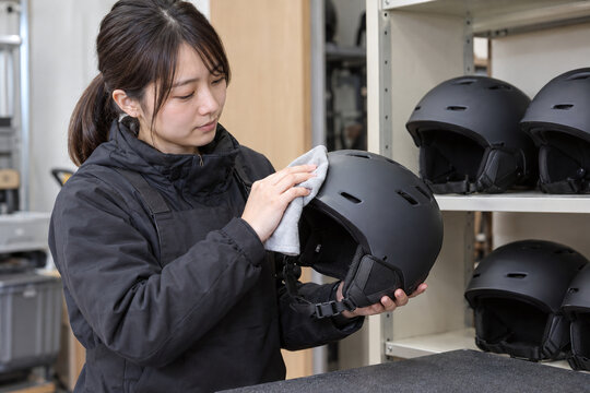 スキー場レンタルスタッフがヘルメットのあご紐を確認する