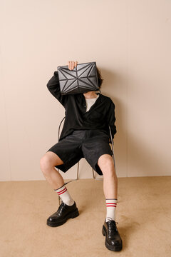 Model Hiding Face With Black Geometric Bag
