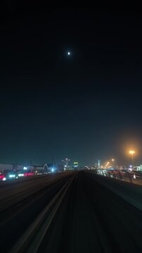DUBAI, UAE - AUGUST 29, 2026: Dubai Metro train travels past Noon, an online retailer, and Emaar signage before entering a station in Dubai UAE at night