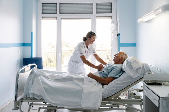 Nurse caring senior patient in hospital bed