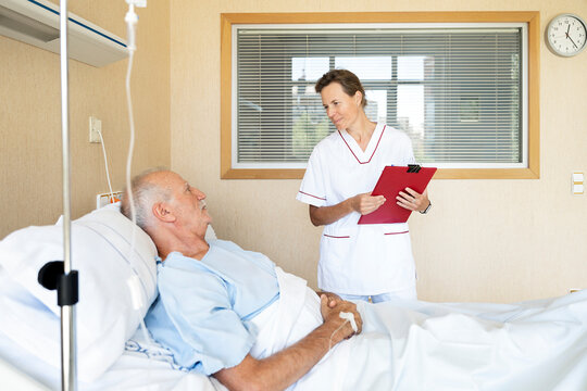 Nurse checking on elderly male patient in hospital