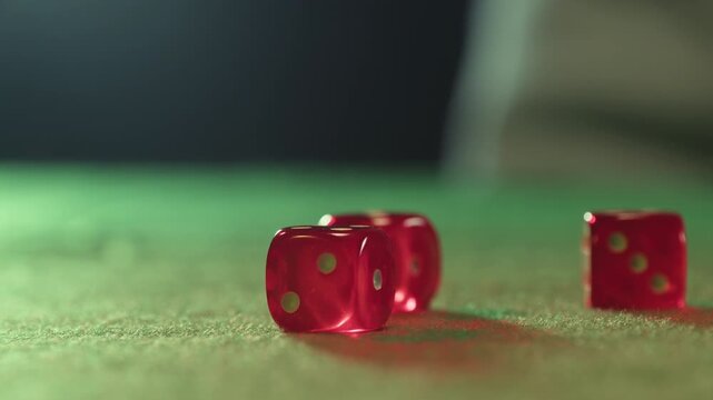 Close up of a player hand throwing two red dice on a green felt casino table during a game of craps, gambling and betting concept with luck and chance.