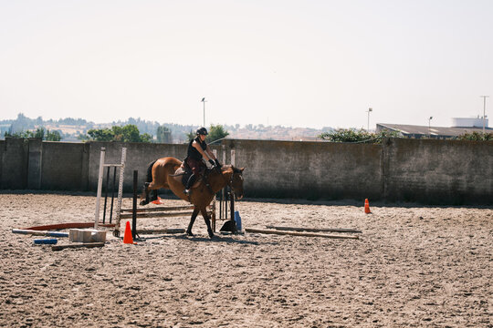 Young horsewoman riding and jumping outdoors