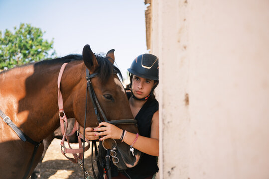 Horsewoman putting the reins on the horse