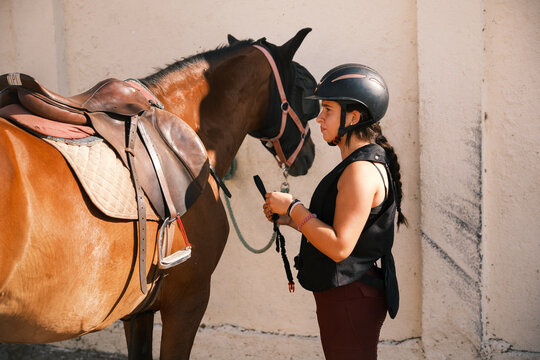 Horsewoman putting the reins on the horse