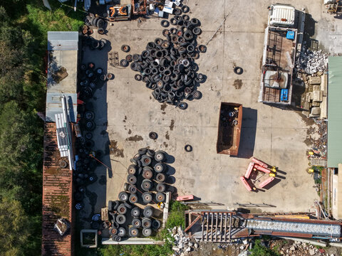 Wantirna South, Australia - 08 September 2026: Aerial view of Knox Transfer Station with piles of discarded tires, industrial waste containers, and machinery on a concrete yard.