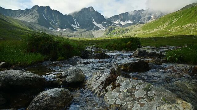 Clear mountain stream flowing over rocks in alpine valley