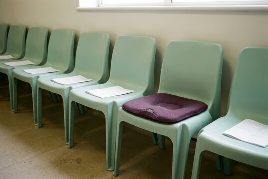 Empty waiting room chairs with mint green seating and worn cushion