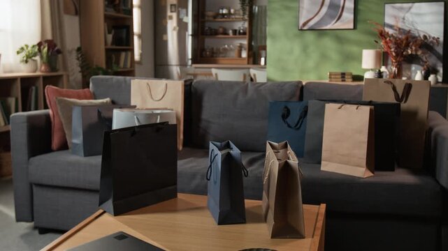 Multiple paper shopping bags standing on sofa and table during panning shot. Ideal for Black Friday sales campaigns, seasonal retail promotions, consumerism, and ecommerce marketing content