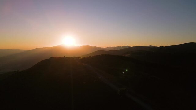 Aerial View of Mountain Sunset Over Silhouetted Peaks and Ridge Road