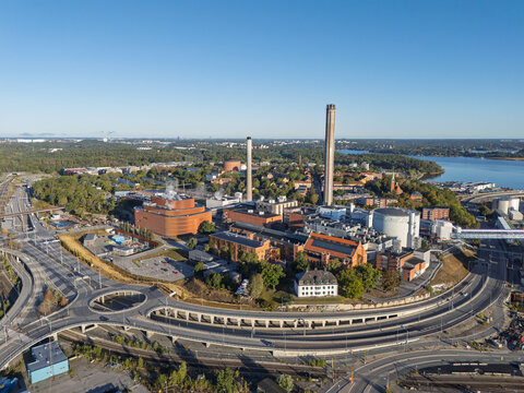 Stockholm, Sweden - 05 September 2026: Aerial view of Stockholm Exergi's combined heat and power plant in Vartahamnen, featuring its tall chimney, industrial buildings, and highway infrastructure.