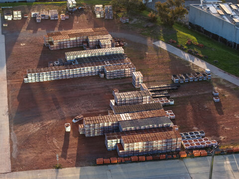 Melbourne, VIC, Australia - 07 September 2026: Aerial view of a tile manufacturing factory yard in Mitcham, with organized stacks of ceramic tiles on a dirt lot and industrial buildings.