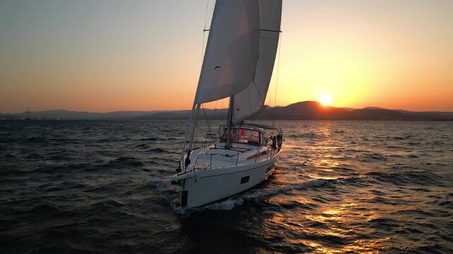 Sailor unfurling sail on yacht at sunset near Saint-Tropez, French Riviera