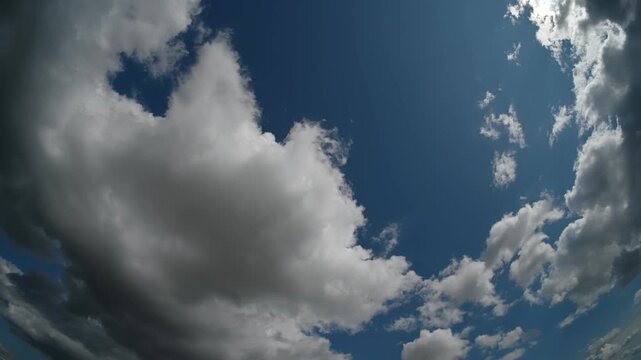 Timelapse of fisheye view white summer clouds moving through a blue sky
