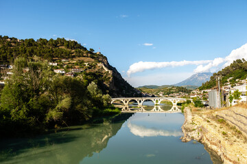 Fototapeta premium Serene views of the Osum River and iconic bridge in Berat, Albania under a clear blue sky