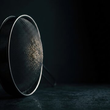 Metal sieve with fine mesh on dark surface