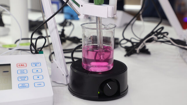Laboratory digital pH meter and magnetic stirrer with pink solution in a beaker