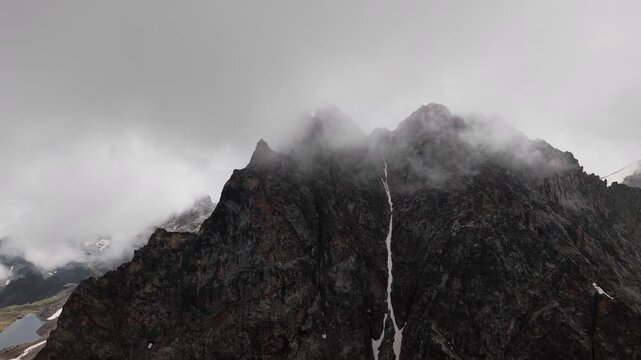 Aerial view of a rugged dark mountain peak with snow