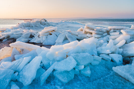 Large ice blocks of sea ice covering a frozen shoreline beneath a winter sky