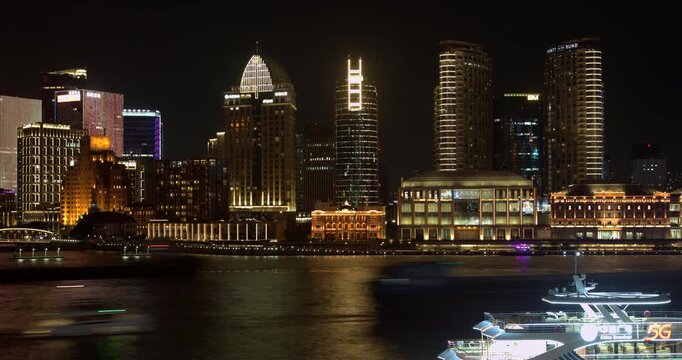 SHANGHAI, CHINA - AUGUST 23, 2026: Tourist cruise boats navigate the Huangpu River past illuminated Bund waterfront buildings at night in SHANGHAI CHINA, in timelapse