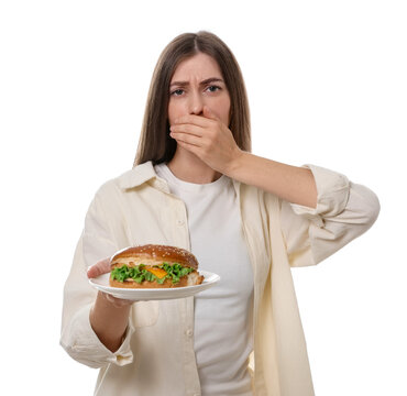 Diet. Woman with hamburger covering her mouth on white background