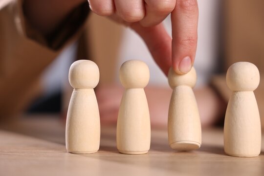 Woman choosing among wooden human figures at table, closeup